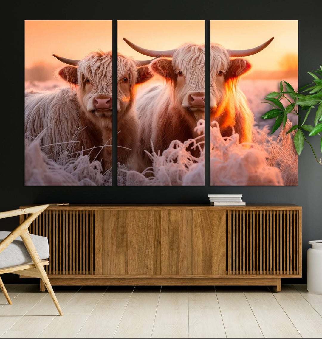 The "Highland Cows at Sunrise Wall Art Canvas Set" beautifully captures a serene and rustic farmhouse aesthetic, portraying two Highland cows in a frosty landscape at sunrise.