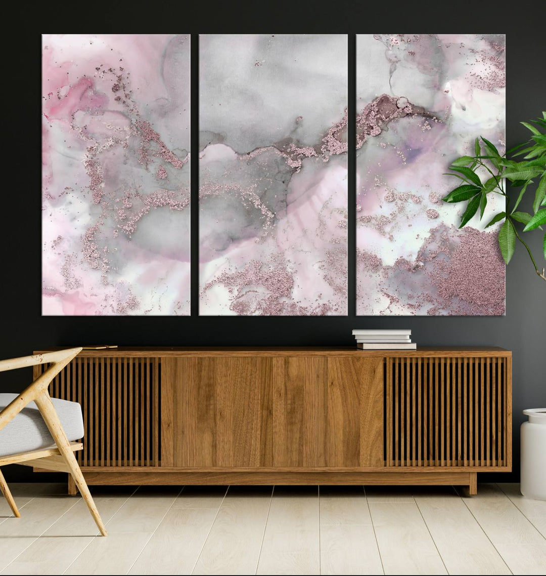 The Rose Marble Abstract Wall Art Canvas Print is a stunning triptych that showcases pink and gray tones, elegantly presented on a dark wall.