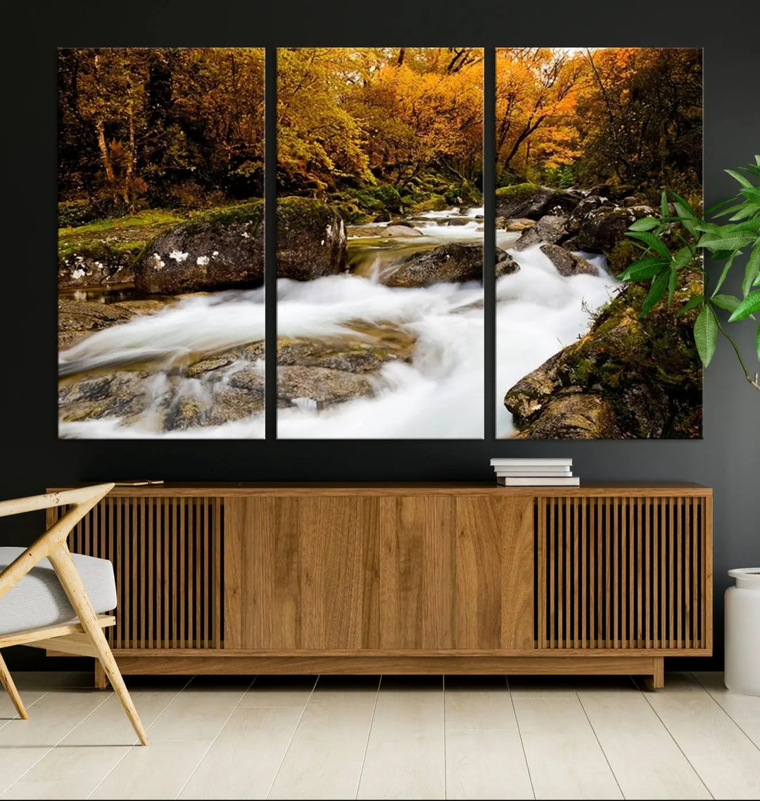 The living room is adorned with the "Wall Art Waterfall Canvas Print River in Forest in Autumn," a triptych on museum-quality canvas showcasing a flowing river surrounded by autumn trees. This ready-to-hang artwork features a UV-protective coating to ensure enduring vibrancy.