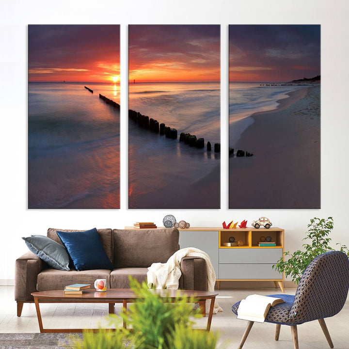 In a modern living room, the Sunset Beach Wall Art Canvas Print is displayed above. This triptych, printed on museum-quality canvas with a UV-protective coating, ensures lasting brilliance. It's ready to hang and brings an elegant touch to your space.