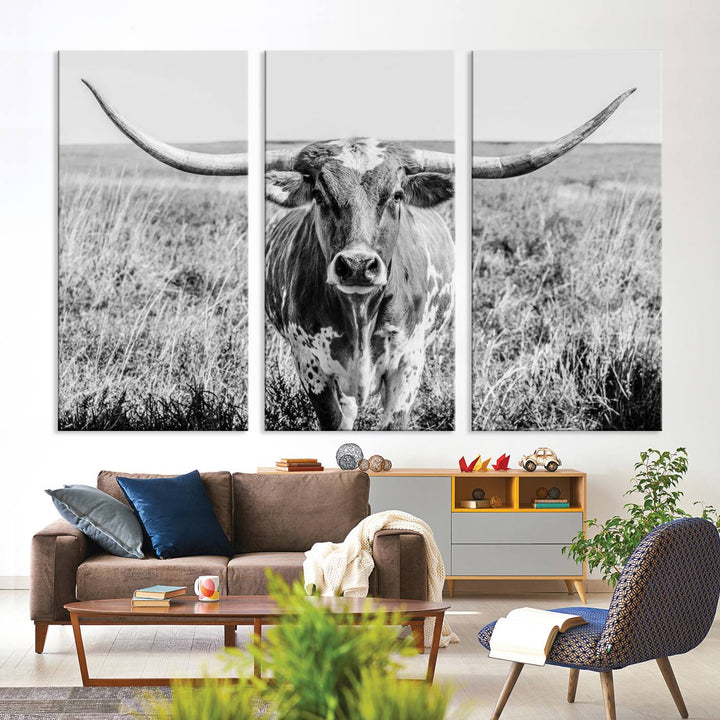 The Texas Cow Longhorn Wall Art Canvas Print is a black and white triptych depicting a cow in a field. It is crafted with museum-quality canvas and features a UV-protective coating.