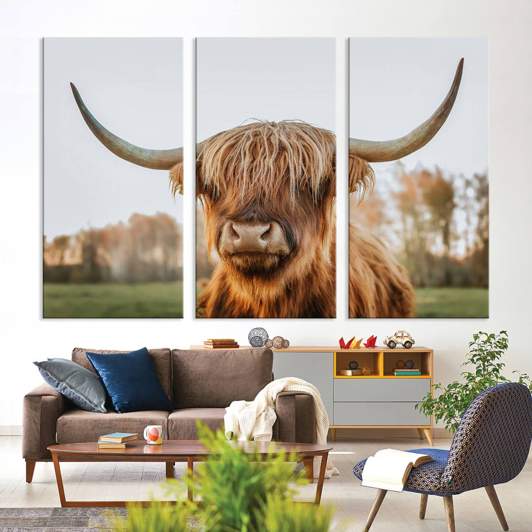 A Highland Cow Animal Scottish Cattle Art Print Farmhouse Wall Art Canvas Print hangs in the living room, adding a touch of rustic farmhouse decor.