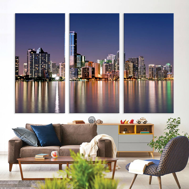 The Miami Skyline Canvas Wall Art Print showcases a vibrant night cityscape and beautifully captures the dazzling colorful lights reflecting on the water. This ready-to-hang triptych adorns the wall, creating a stunning visual centerpiece.