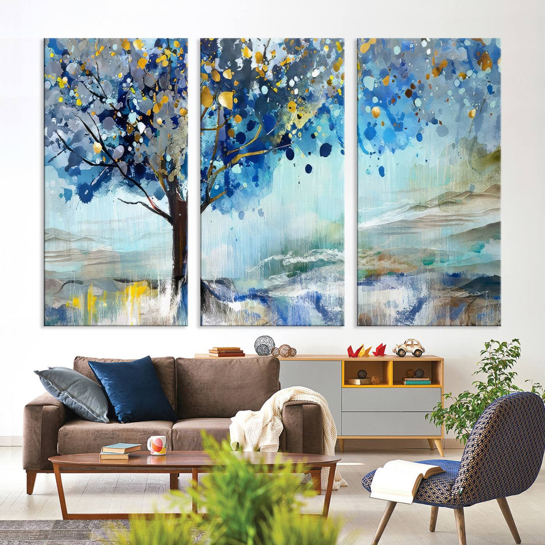 A modern living room features a three-panel Watercolor Style Abstract Tree Printing Wall Art Canvas in vibrant blue and yellow, crafted on museum-quality material.