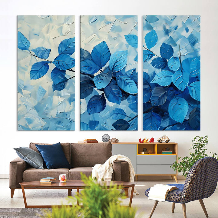 The contemporary living room is highlighted by the Abstract Blue Leaf Wall Art Canvas Print on the wall. The hand-assembled framed art enhances the room's vibrant decor, crafting a gallery-worthy ambience.