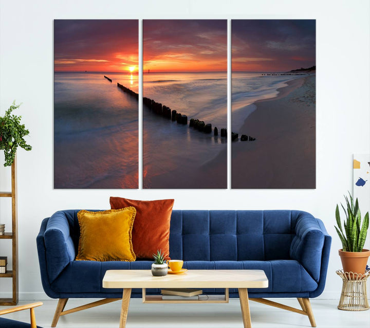 In a modern living room, the Sunset Beach Wall Art Canvas Print is displayed above. This triptych, printed on museum-quality canvas with a UV-protective coating, ensures lasting brilliance. It's ready to hang and brings an elegant touch to your space.