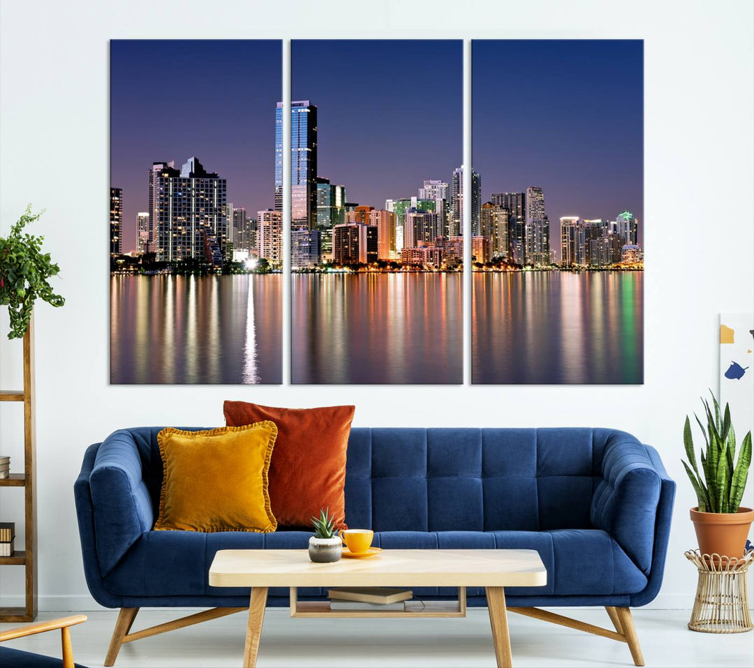 The Miami Skyline Canvas Wall Art Print showcases a vibrant night cityscape and beautifully captures the dazzling colorful lights reflecting on the water. This ready-to-hang triptych adorns the wall, creating a stunning visual centerpiece.