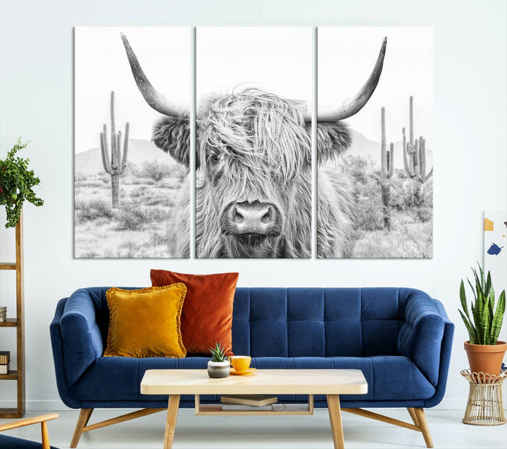 The "Rustic Charm | Cow Longhorn Black White Bighorn Wall Art Canvas Print" is a stunning triptych that showcases a highland cow with long horns set against a desert landscape with cacti in the background. This farmhouse wall art elevates any room into a rustic haven with its gallery-quality canvas.