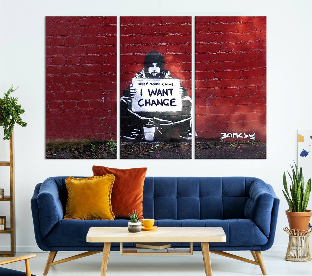 The living room showcases a triptych of stencil artwork on museum-quality canvas, featuring the Banksy I Want Change Graffiti Abstract Wall Art Canvas Print. This captivating piece depicts a person holding a sign that says "I want change" and is finished with a UV-protective coating to ensure long-lasting beauty.