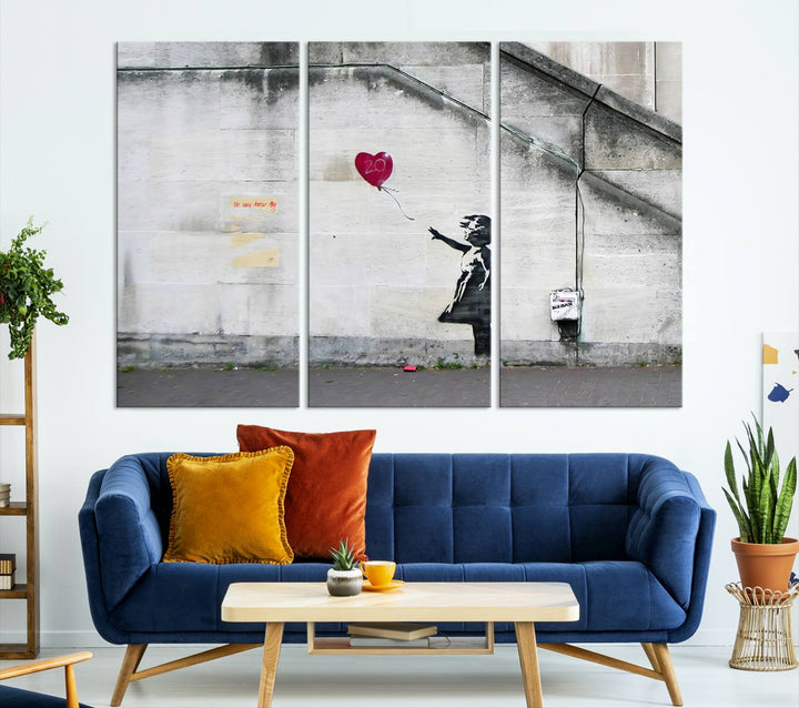 The "Girl with a Balloon Banksy Street Graffiti Art Canvas Print" is a gallery-quality wall art piece that features an image of a girl releasing a heart-shaped balloon. Handmade in the USA, this canvas artwork brings charm and emotion to any room.