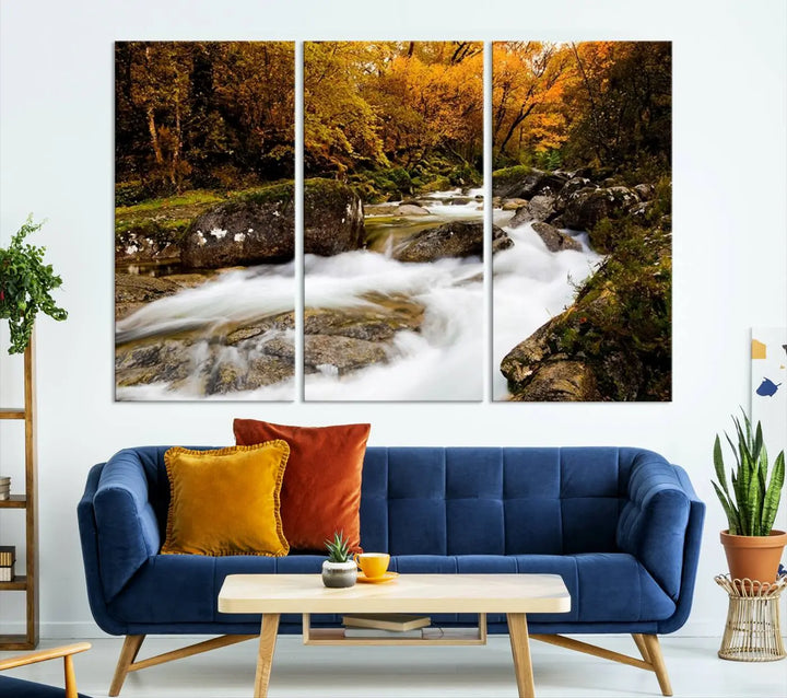 The living room is adorned with the "Wall Art Waterfall Canvas Print River in Forest in Autumn," a triptych on museum-quality canvas showcasing a flowing river surrounded by autumn trees. This ready-to-hang artwork features a UV-protective coating to ensure enduring vibrancy.