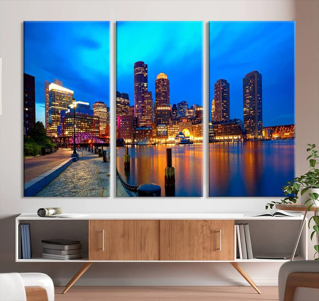 A triptych of the "Boston City Lights Night Blue Skyline Cityscape View Wall Art Canvas Print" adorns the wall. This museum-quality canvas artwork is ready to hang and includes a UV-protective coating for lasting brilliance.