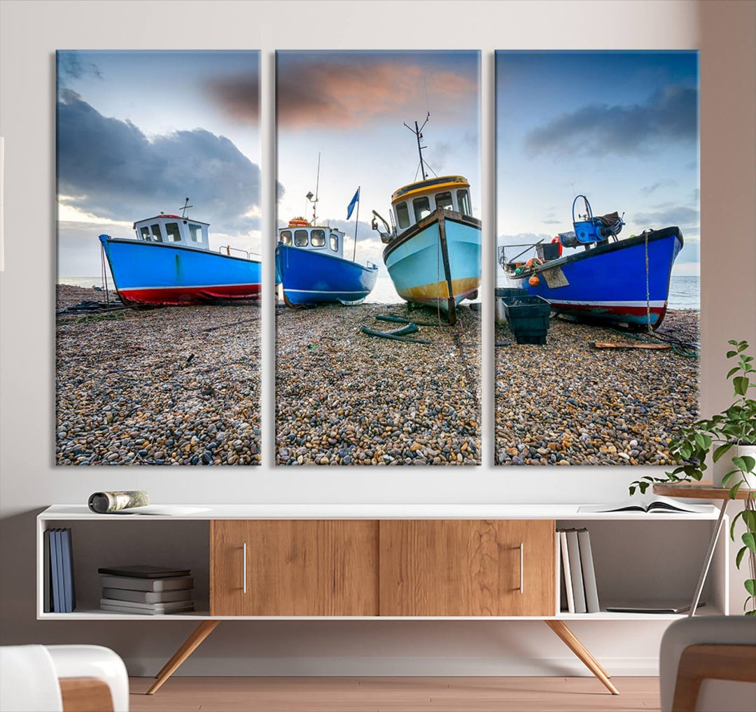 The "Big Boats On The Beach Wall Art Canvas Print" is a stunning piece featuring three museum-quality panels depicting fishing boats on a pebbled shore. Ready to hang and featuring UV-protective coating, it serves as an elegant addition to your home décor.