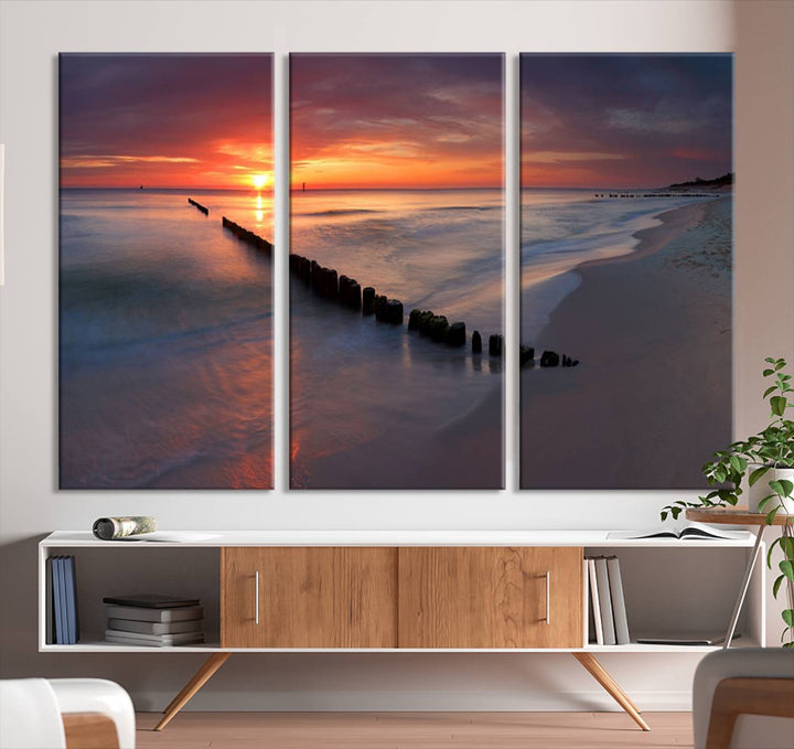 In a modern living room, the Sunset Beach Wall Art Canvas Print is displayed above. This triptych, printed on museum-quality canvas with a UV-protective coating, ensures lasting brilliance. It's ready to hang and brings an elegant touch to your space.