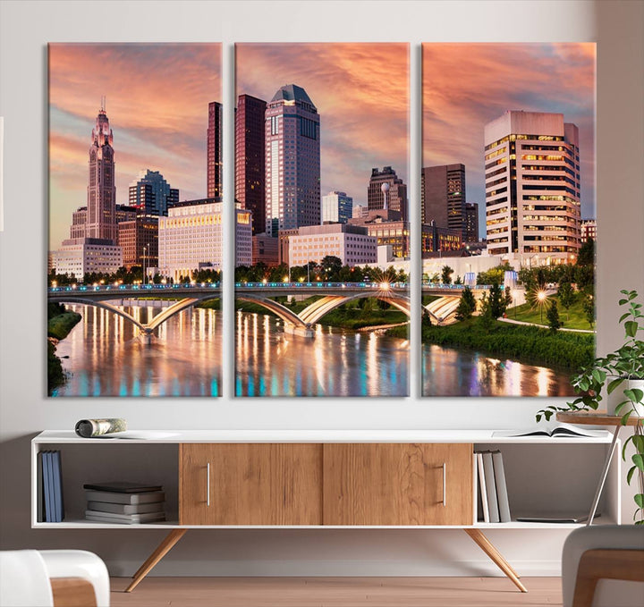 The "Columbus City Lights Sunset Orange Cloudy Skyline Cityscape View" wall art is featured on the wall. This triptych is printed on museum-quality canvas and includes a UV-protective coating, ensuring lasting vibrancy.