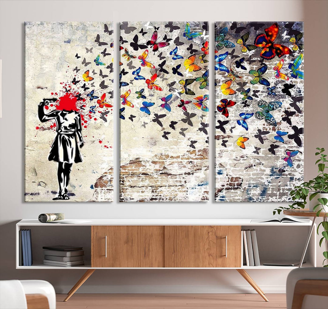 The Banksy Art Butterfly Girl Explosion Canvas showcases a dynamic figure with butterflies bursting from their head, set against a textured wall background. This vibrant urban graffiti piece is perfect for modern interiors and comes ready to hang.