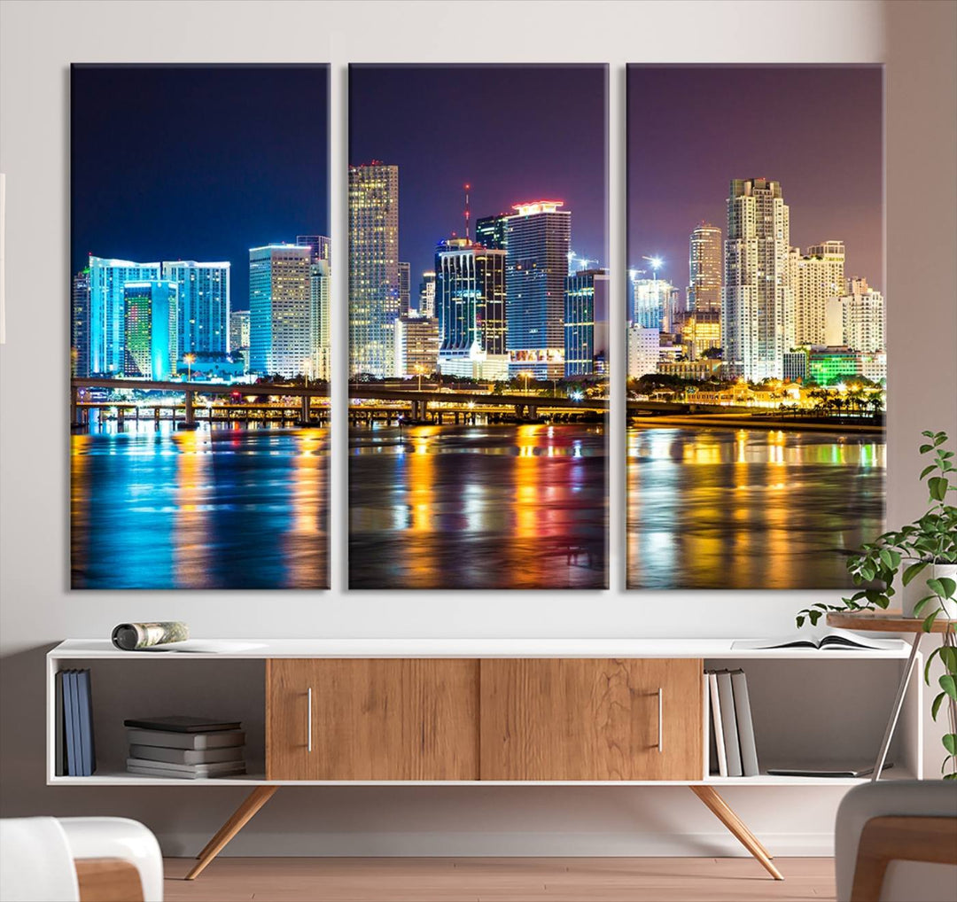 The Wall Art MIAMI Canvas Print features a stunning triptych of a city skyline at night, with vibrant lights reflecting on the water. This gallery-wrapped piece on museum-quality canvas delivers an exquisite finish.