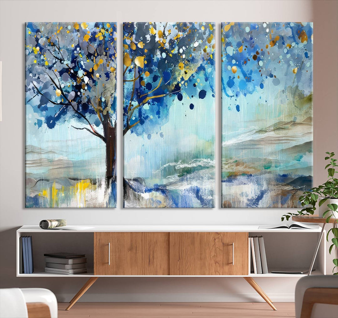 A modern living room features a three-panel Watercolor Style Abstract Tree Printing Wall Art Canvas in vibrant blue and yellow, crafted on museum-quality material.