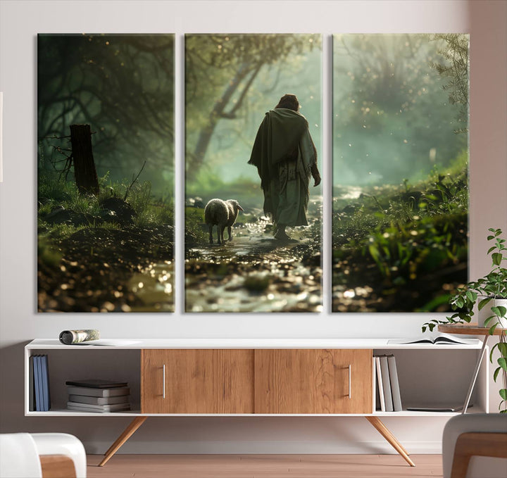 The wall art piece, titled "Jesus Shepherd a Lost Lamb Canvas Wall Art Print," is suspended on the wall and depicts a robed figure and a lamb wandering along a forest path.