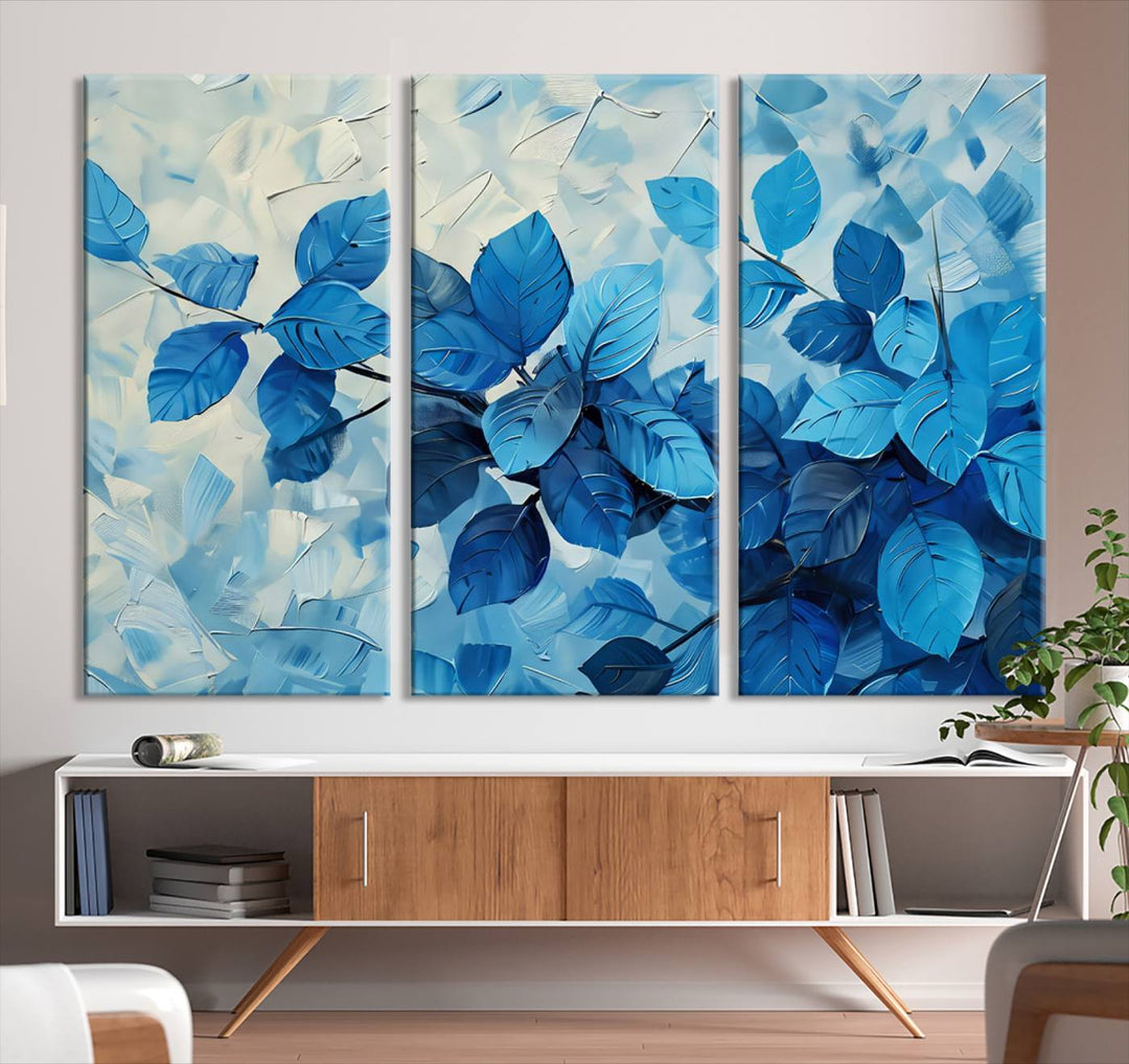 The contemporary living room is highlighted by the Abstract Blue Leaf Wall Art Canvas Print on the wall. The hand-assembled framed art enhances the room's vibrant decor, crafting a gallery-worthy ambience.