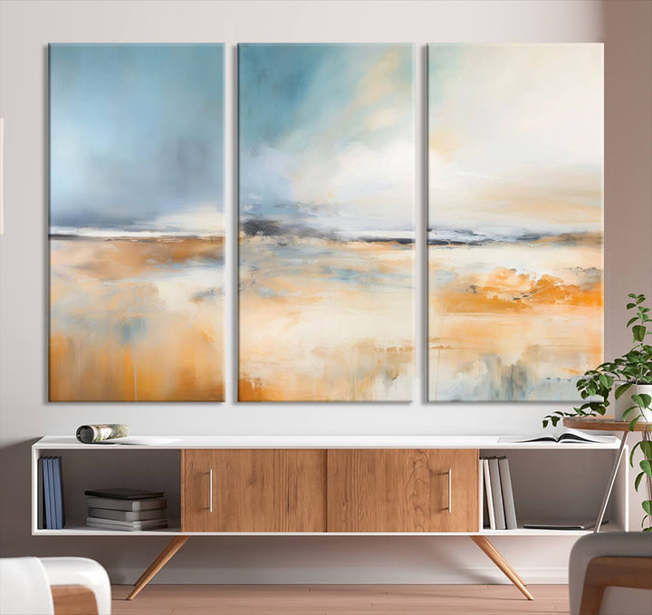 The Abstract Landscape Wall Art Canvas Print, featuring warm tones of orange and blue, is displayed on a dark wall.