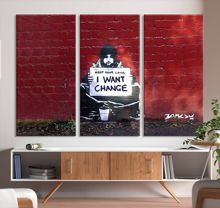 The living room showcases a triptych of stencil artwork on museum-quality canvas, featuring the Banksy I Want Change Graffiti Abstract Wall Art Canvas Print. This captivating piece depicts a person holding a sign that says "I want change" and is finished with a UV-protective coating to ensure long-lasting beauty.