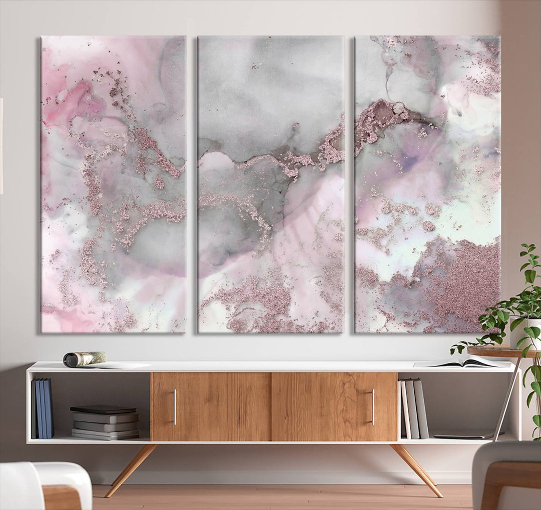 The Rose Marble Abstract Wall Art Canvas Print is a stunning triptych that showcases pink and gray tones, elegantly presented on a dark wall.