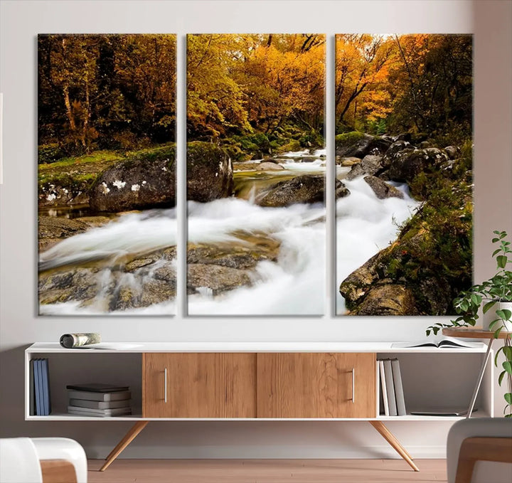 The living room is adorned with the "Wall Art Waterfall Canvas Print River in Forest in Autumn," a triptych on museum-quality canvas showcasing a flowing river surrounded by autumn trees. This ready-to-hang artwork features a UV-protective coating to ensure enduring vibrancy.