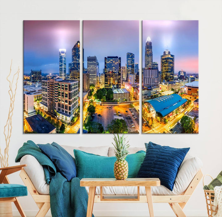 The living room features three large pieces of the *Charlotte City Lights Sunset Purple Skyline Cityscape View Wall Art Canvas Print*. Crafted on gallery-wrapped, museum-quality canvas with UV-protective coating, they grace the wall and add an artistic flair to the space.