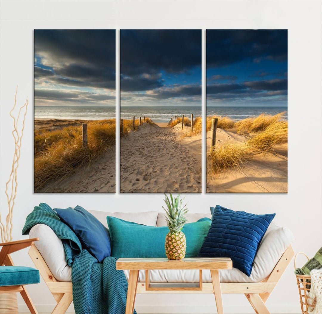 The Ocean Beach Dark Clouds Wall Art Canvas Print is a breathtaking triptych depicting a sandy beach path with tall grasses under an intense cloudy sky. It is crafted on museum-quality canvas with UV protection.