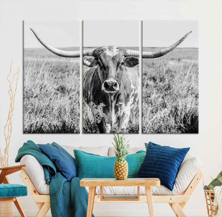 The Texas Cow Longhorn Wall Art Canvas Print is a black and white triptych depicting a cow in a field. It is crafted with museum-quality canvas and features a UV-protective coating.