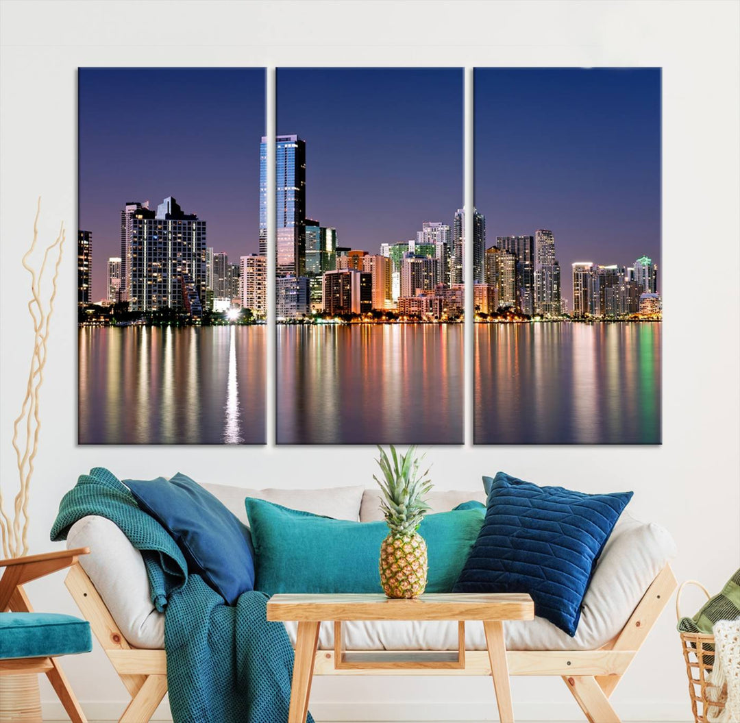 The Miami Skyline Canvas Wall Art Print showcases a vibrant night cityscape and beautifully captures the dazzling colorful lights reflecting on the water. This ready-to-hang triptych adorns the wall, creating a stunning visual centerpiece.