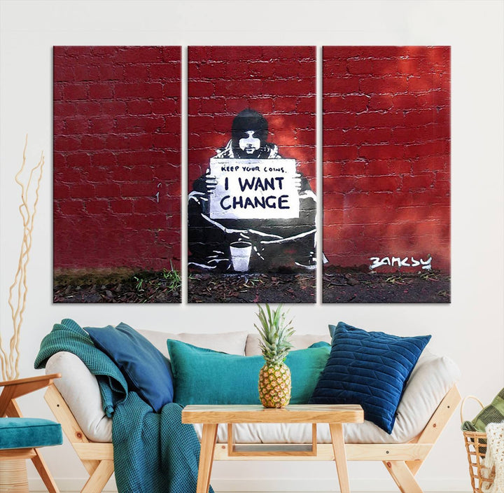 The living room showcases a triptych of stencil artwork on museum-quality canvas, featuring the Banksy I Want Change Graffiti Abstract Wall Art Canvas Print. This captivating piece depicts a person holding a sign that says "I want change" and is finished with a UV-protective coating to ensure long-lasting beauty.