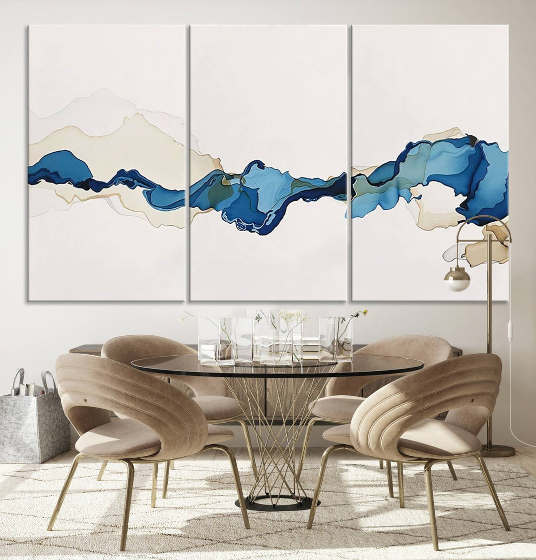 The modern living room showcases a set of three canvas prints with abstract blue art on museum-quality materials.