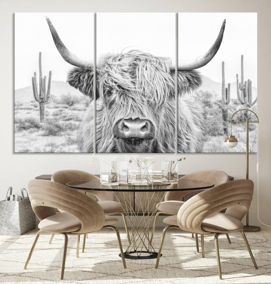 The "Rustic Charm | Cow Longhorn Black White Bighorn Wall Art Canvas Print" is a stunning triptych that showcases a highland cow with long horns set against a desert landscape with cacti in the background. This farmhouse wall art elevates any room into a rustic haven with its gallery-quality canvas.