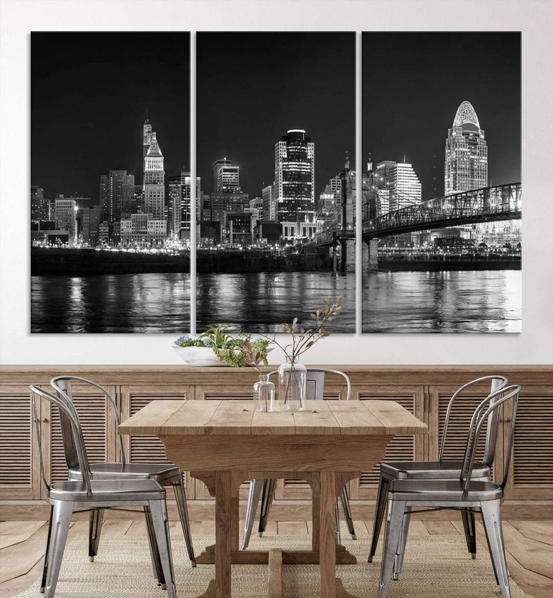 The Cincinnati City Lights Skyline Black and White Wall Art Cityscape Canvas Print elegantly adorns a modern living room. This museum-quality canvas triptych of a city skyline is enhanced by hand-assembled frames for added finesse, and you can enjoy free shipping on this stunning home addition.