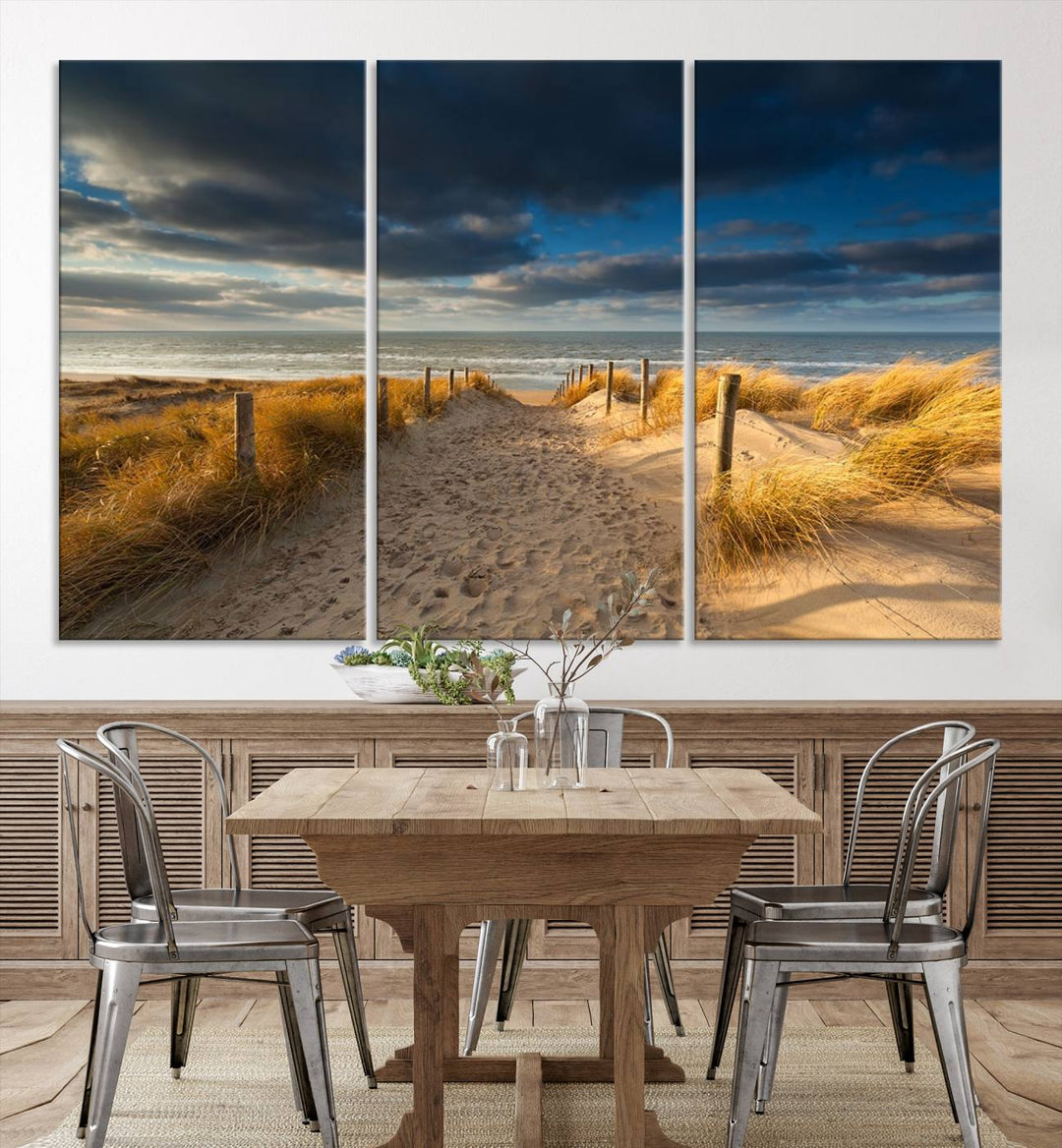 The Ocean Beach Dark Clouds Wall Art Canvas Print is a breathtaking triptych depicting a sandy beach path with tall grasses under an intense cloudy sky. It is crafted on museum-quality canvas with UV protection.