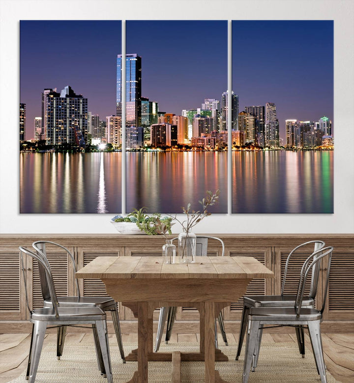 The Miami Skyline Canvas Wall Art Print showcases a vibrant night cityscape and beautifully captures the dazzling colorful lights reflecting on the water. This ready-to-hang triptych adorns the wall, creating a stunning visual centerpiece.