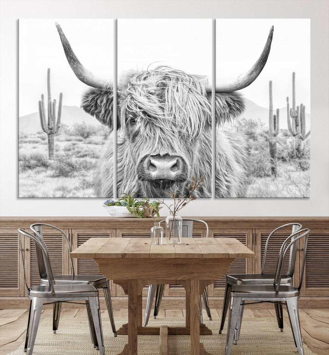 The "Rustic Charm | Cow Longhorn Black White Bighorn Wall Art Canvas Print" is a stunning triptych that showcases a highland cow with long horns set against a desert landscape with cacti in the background. This farmhouse wall art elevates any room into a rustic haven with its gallery-quality canvas.