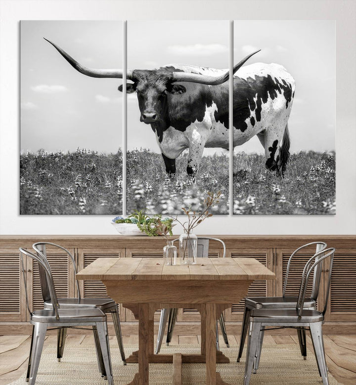 The Texas Black White Highland Longhorn Cow Wall Art Canvas Print, a gallery-quality triptych, elegantly adorns the wall, showcasing a striking black-and-white depiction of a longhorn cow in a field.