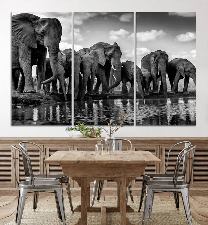 A stunning "Wall Art Animal Canvas Print" featuring a black and white photo of a herd of elephants drinking water is elegantly displayed, gallery wrapped on museum-quality canvas.