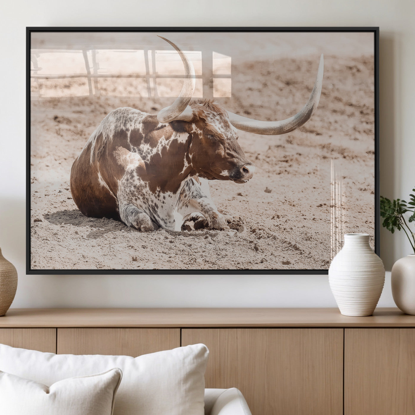 Texas Longhorn bull resting on dusty ground with warm tones, ideal for rustic western or farmhouse-themed wall decor.