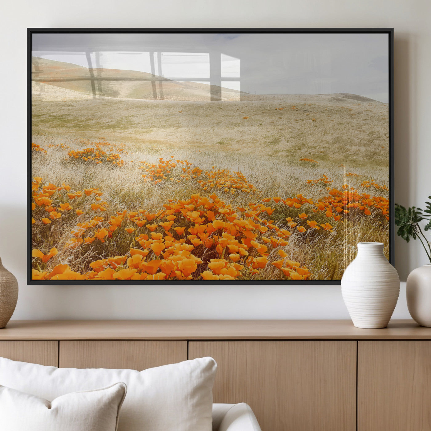 A golden field with vibrant orange poppies blooming across rolling hills under a soft, sunlit sky, creating a warm and rustic landscape.