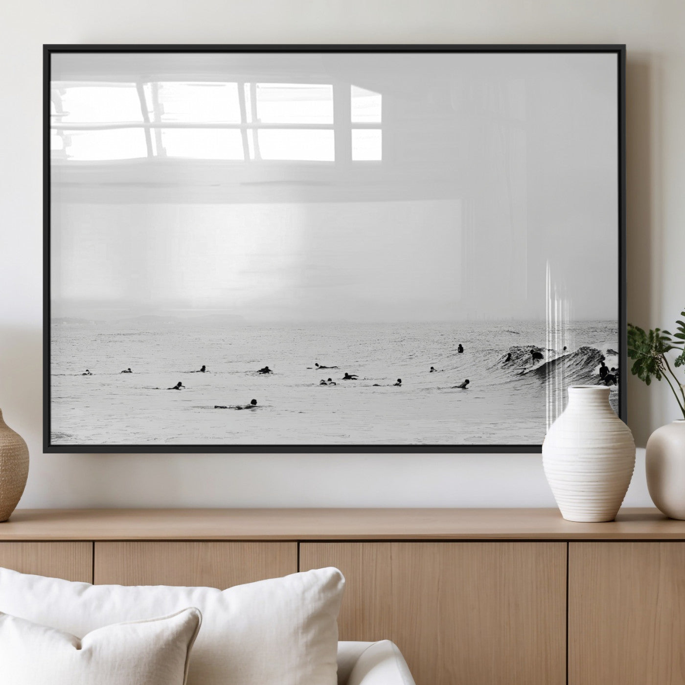 A group of surfers floating in the ocean, waiting for waves under a vast, moody sky, captured in black and white.