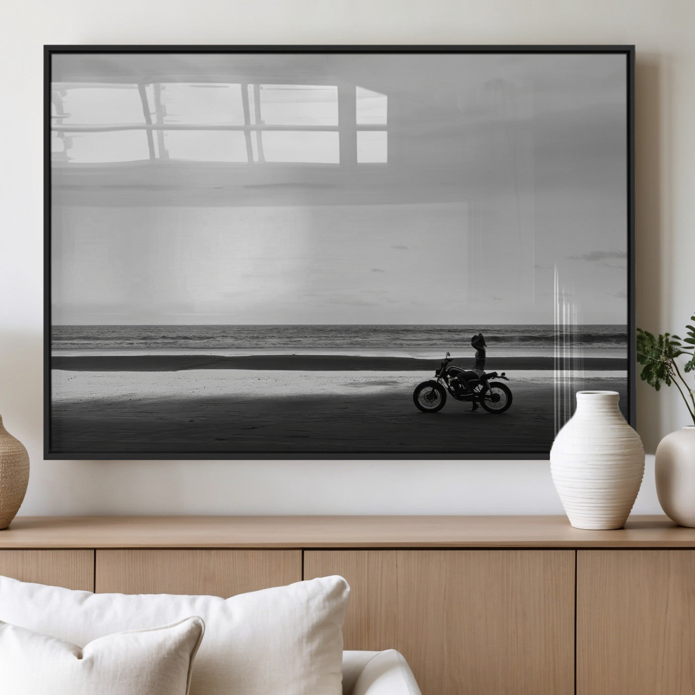 A motorcyclist on a vast beach, gazing at the ocean, capturing a moody and tranquil coastal adventure in black and white.