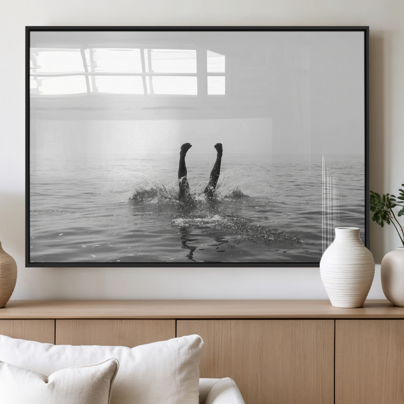 A black and white minimalist water scene capturing a playful splash as a swimmer dives upside down, creating a carefree and artistic aquatic aesthetic.
