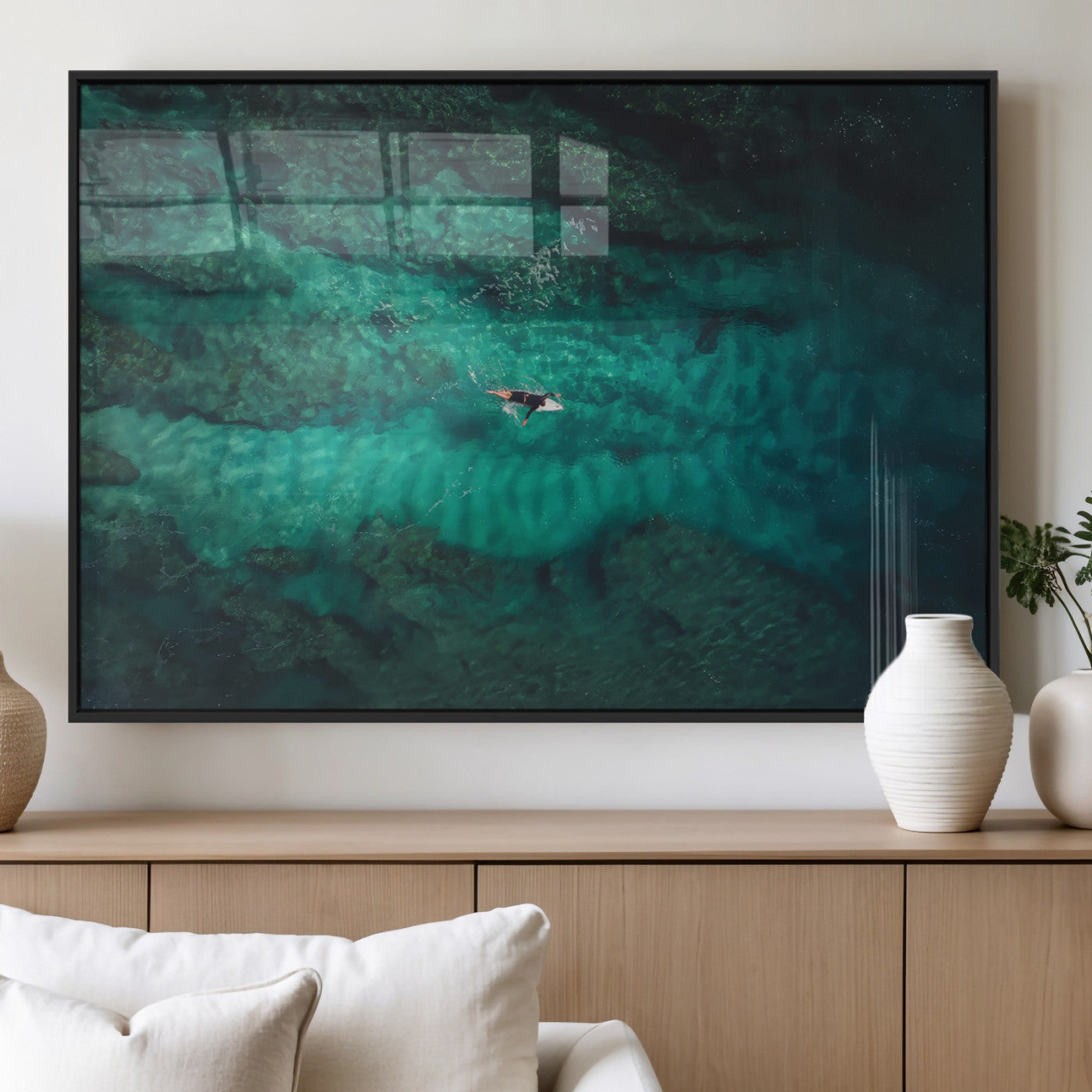 An aerial view of a solo surfer paddling through crystal-clear turquoise waters over a sunlit reef, capturing the beauty and serenity of open water surfing.