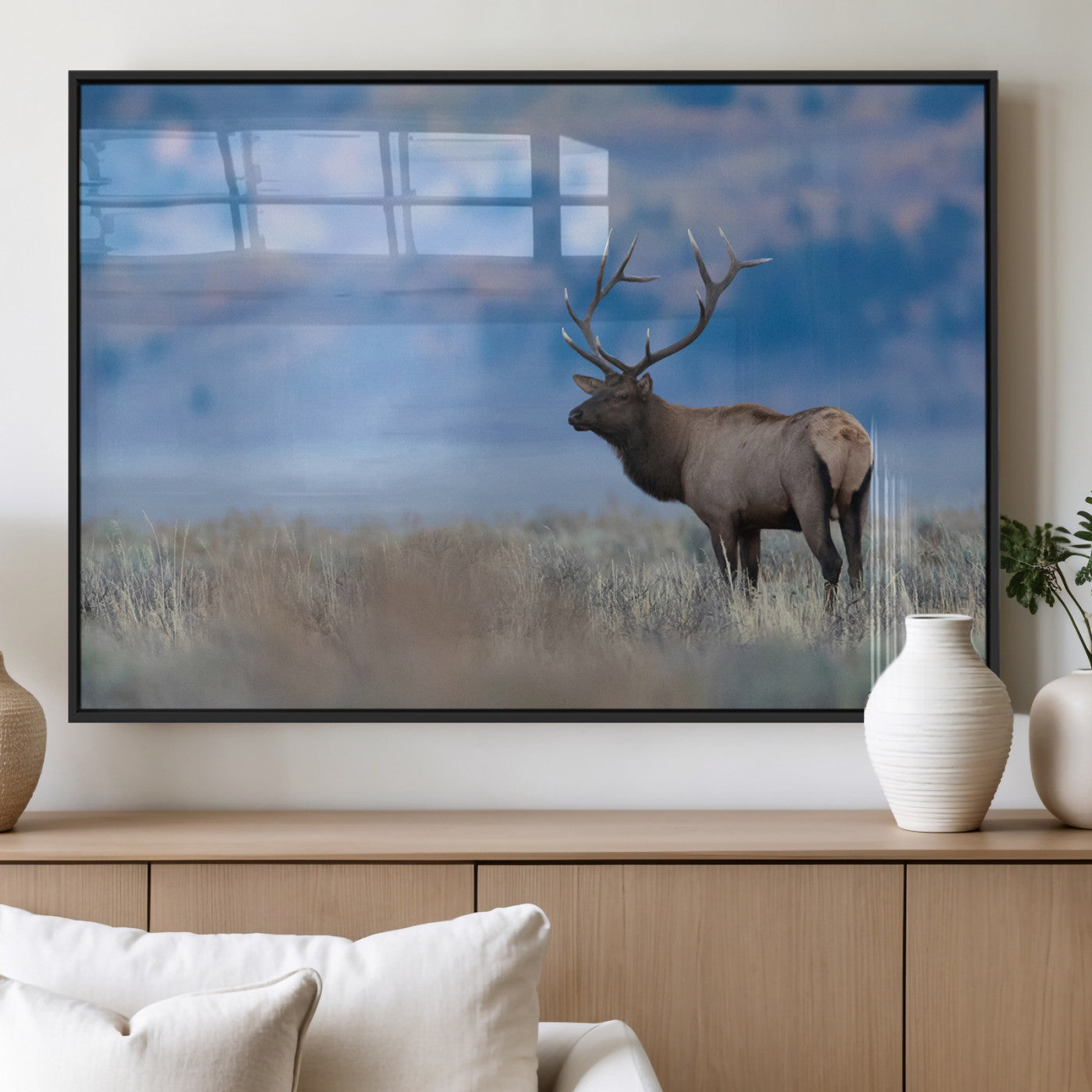 Elk with large antlers standing in open field, mountains blurred in background, perfect for rustic cabin or lodge-style decor.