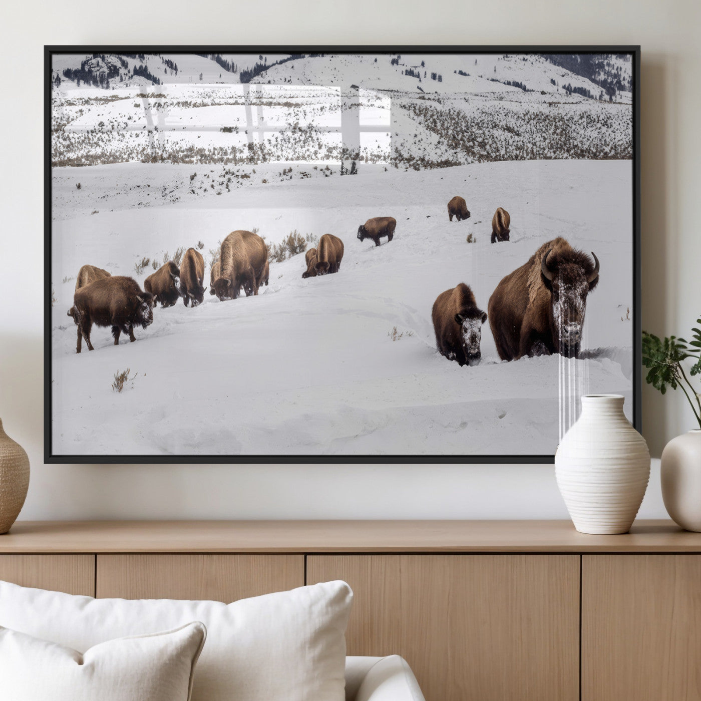 A herd of bison walking through deep snow in a mountain valley, perfect for rustic, cabin or western-themed wall decor.