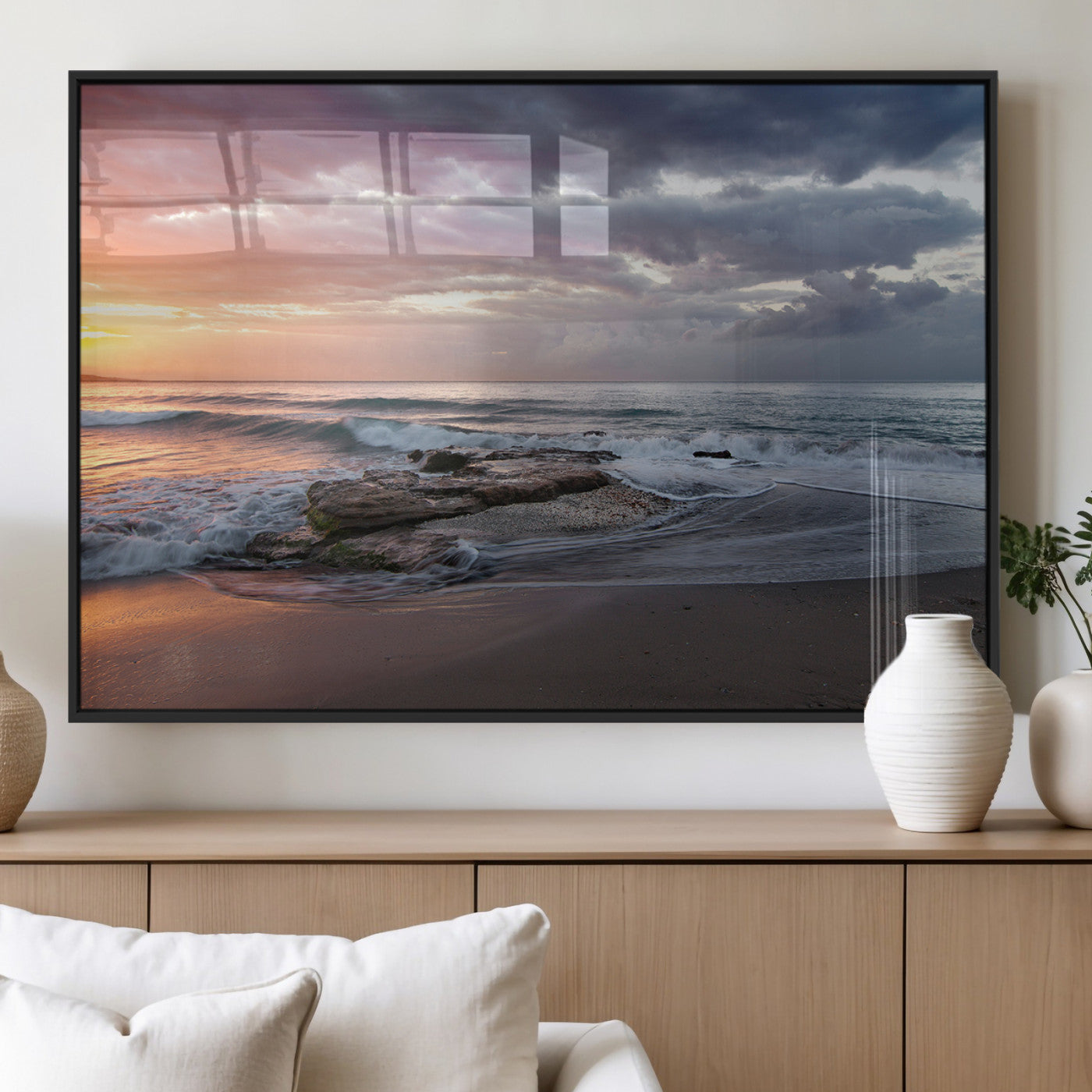 Dramatic sunset over a rocky shoreline with ocean waves gently reaching the sandy beach, creating a serene and coastal atmosphere.